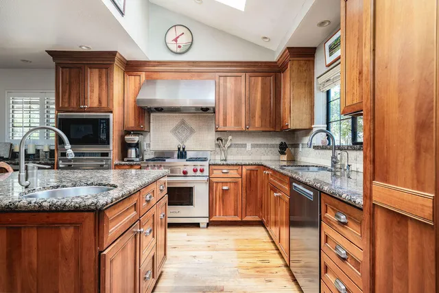 a kitchen with stainless steel appliances granite countertop a sink stove and cabinets