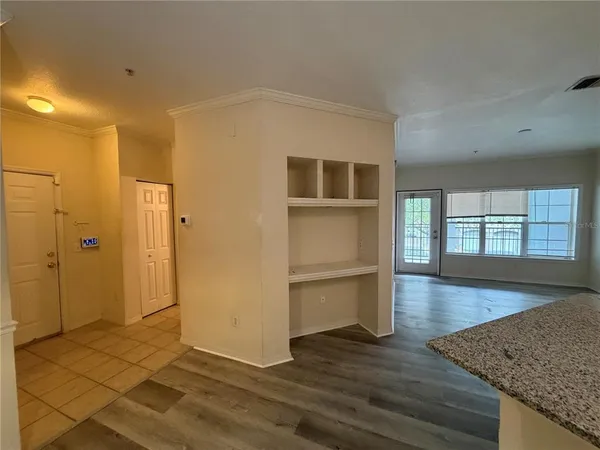 a view of empty room with wooden floor and kitchen