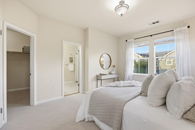 a bedroom with a bed large mirror and a large window