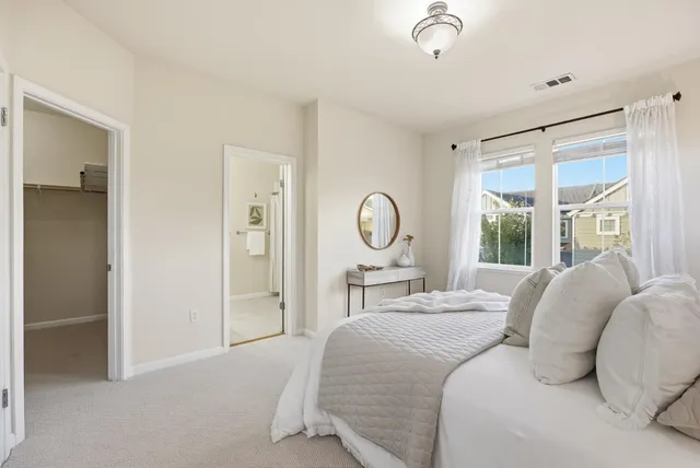 a bedroom with a bed large mirror and a large window