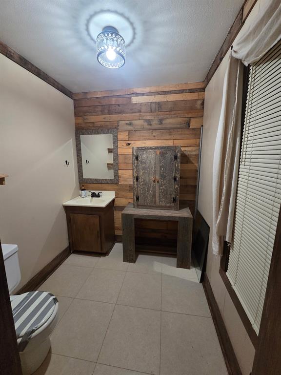 301 Old Plain Dealing Road Benton, LA 71006 - Photo 16 of 19 Powder room featuring a shiplap accent wall, tile flooring, and a crystal flush-mount light fixture