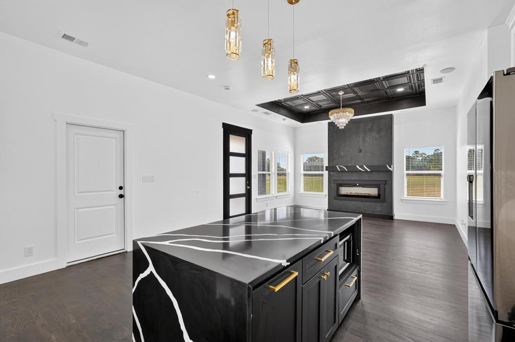 102 Shadywood Road Trinidad, TX 75163 - Photo 7 of 24 Central kitchen island featuring a black countertop with white veining, gold hardware, and built-in microwave