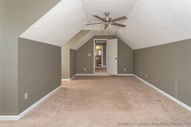 an empty room with chandelier fan and windows