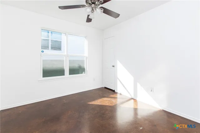 an empty room with a window and hardwood floor