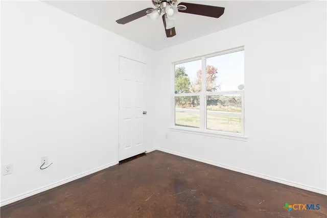 an empty room with a window and a ceiling fan