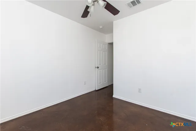 an empty room with a ceiling fan and carpet