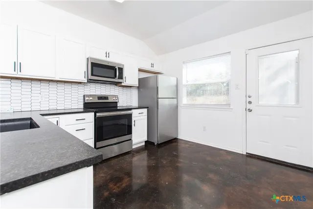 a kitchen with stainless steel appliances granite countertop a refrigerator a stove a sink and a microwave