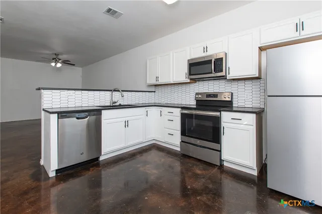 a kitchen with a stove white cabinets and stainless steel appliances