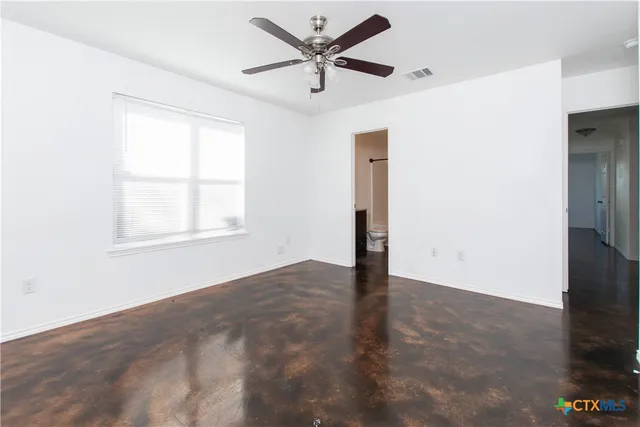 an empty room with window and a ceiling fan