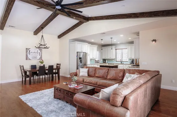 a living room with furniture wooden floor and a kitchen view