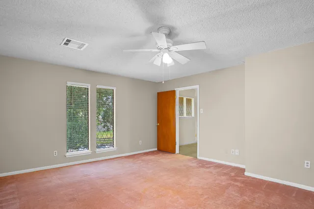 an empty room with windows and fan