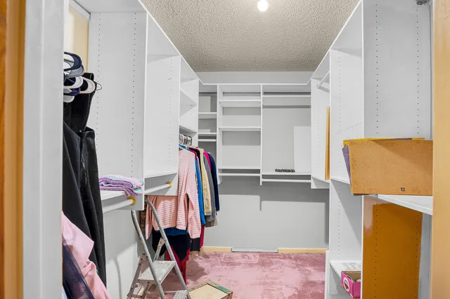 a view of walk in closet with clothes and shoes