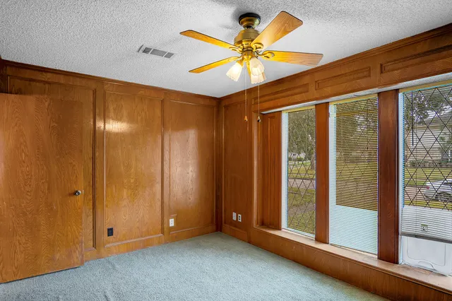 an empty room with windows and fan