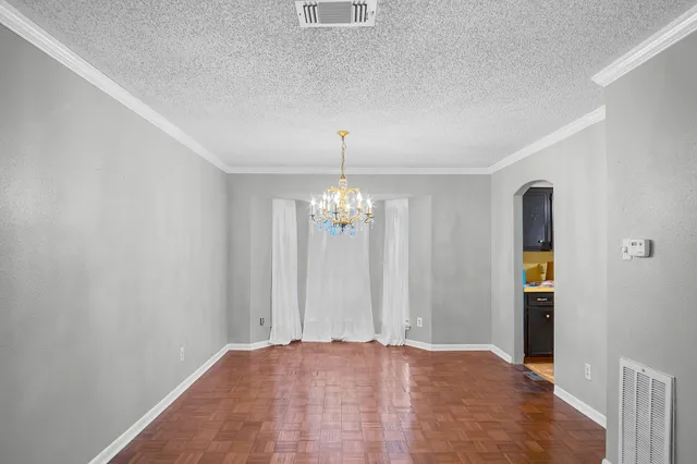 a view of an empty room with window and chandelier fan