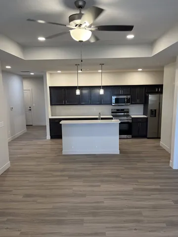 a view of kitchen with granite countertop stainless steel appliances and wooden floor