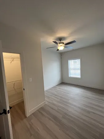 an empty room with wooden floor cabinet and windows