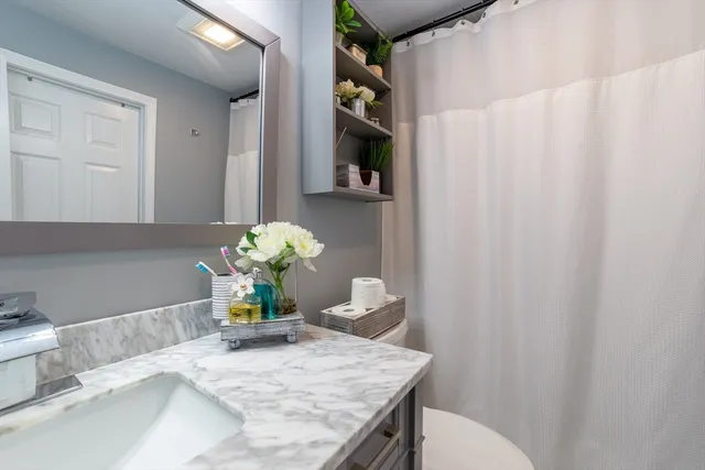 a bathroom with a granite countertop sink a toilet and a shower