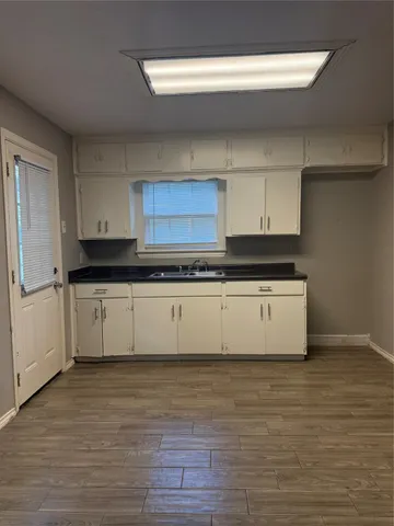 a large white kitchen with granite countertop a stove a sink and dishwasher with wooden floor