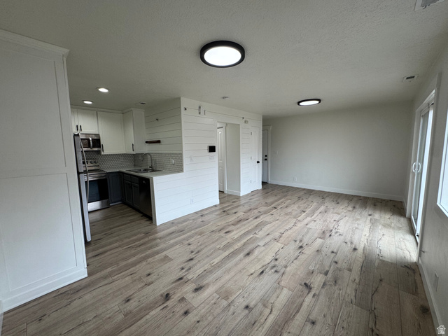 608 South 500 West, Unit 3 Provo, UT 84601 - Photo 7 of 35 Open-concept living area featuring wood-finish flooring, a contemporary kitchen, stainless steel appliances, white cabinetry, and shiplap accents