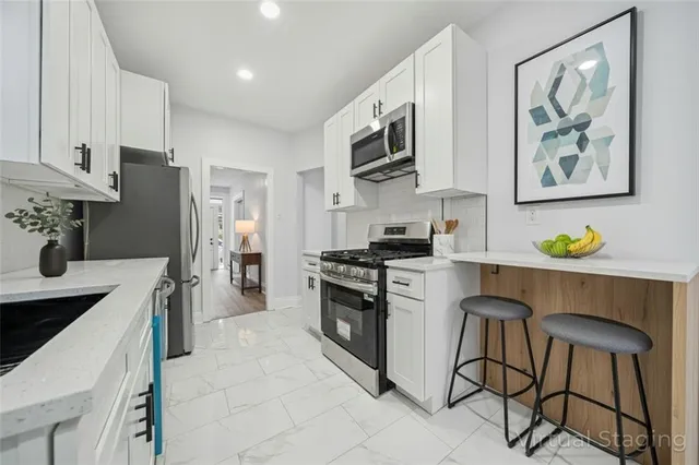 a kitchen with stainless steel appliances granite countertop a refrigerator a stove a microwave a sink and white cabinets with wooden floor