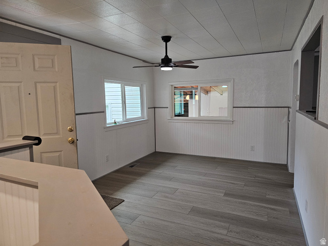 744 Royal Street Helper, UT 84526 - Photo 4 of 33 Unfurnished dining area featuring light wood-style flooring, a ceiling fan, and wainscoting