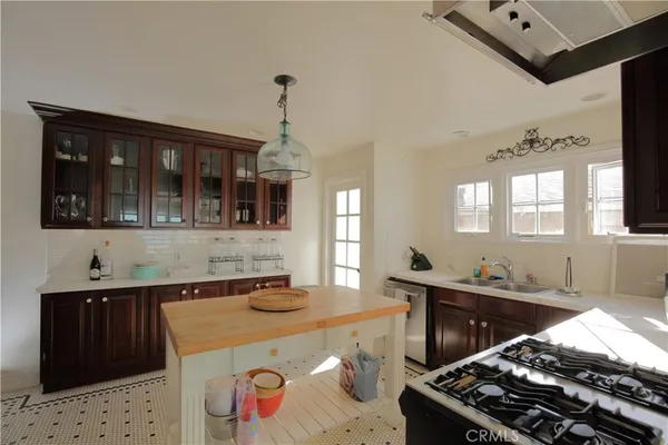 a kitchen with a stove a refrigerator a sink a dining table and chairs with wooden floor