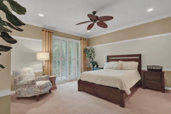 a bedroom with a large bed and a chandelier fan