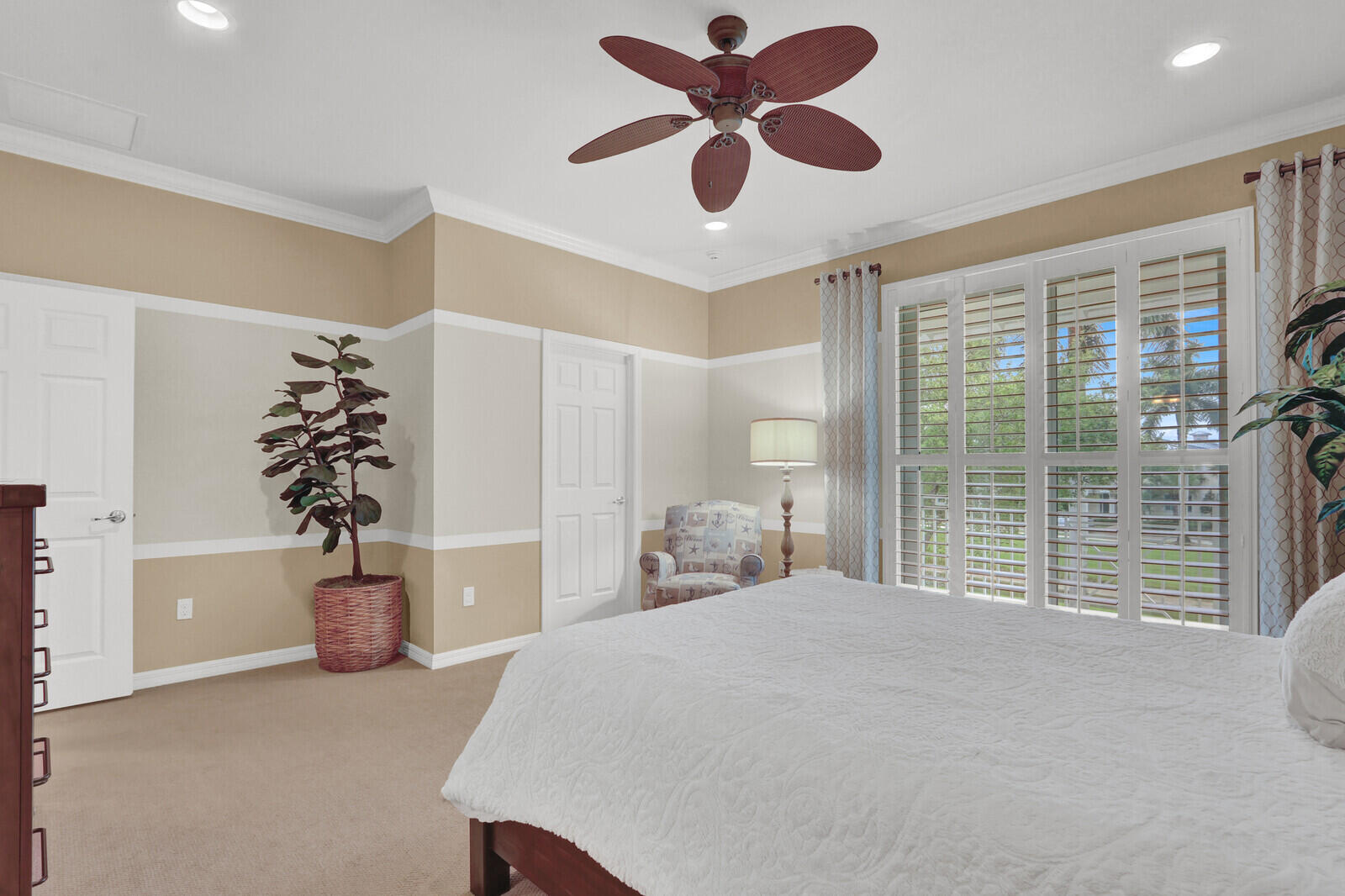 3277 East Mallory Boulevard Jupiter, FL 33458 - Photo 19 of 44 a bedroom with a large bed and a chandelier fan