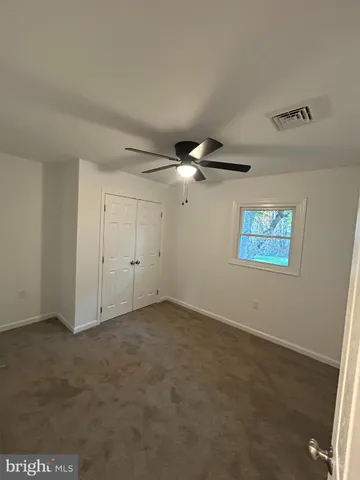 an empty room with a ceiling fan and window