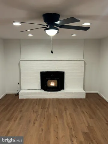 a view of an empty room with wooden floor and a fireplace