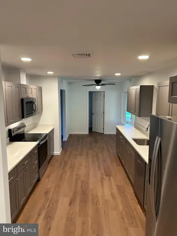 a large kitchen with a center island wooden floor stainless steel appliances and cabinets