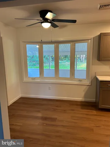 a view of an empty room with a window and wooden floor