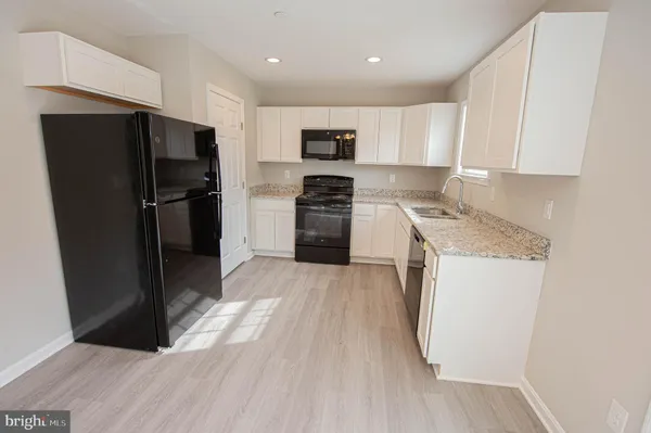 a kitchen with stainless steel appliances granite countertop a refrigerator a stove a sink and a microwave