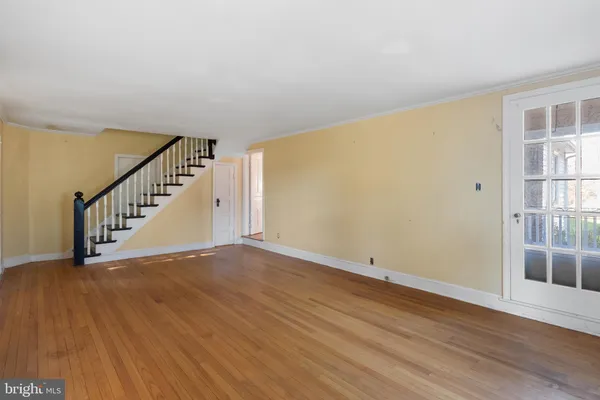 a view of an empty room with wooden floor and stairs