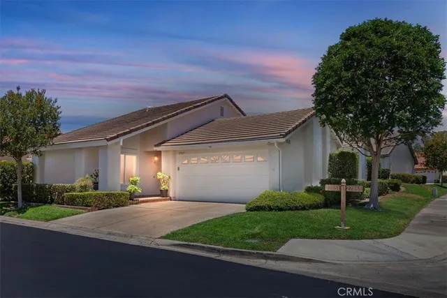a front view of a house with a garden and trees