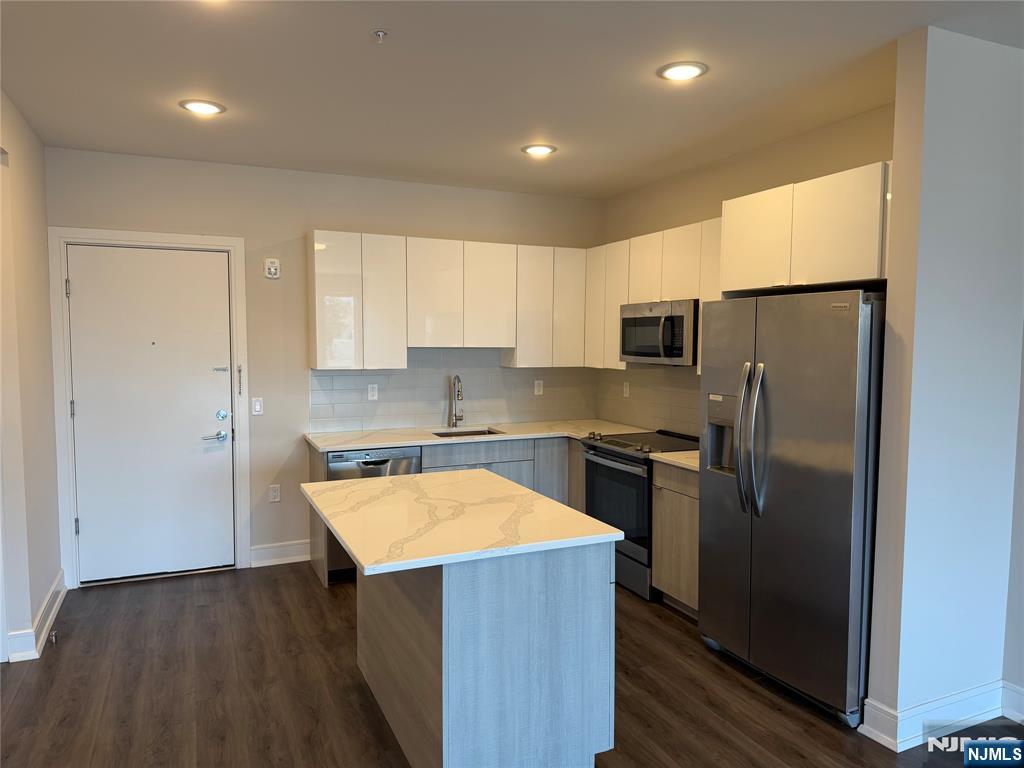 470 Main Street, Unit 412 Fort Lee, NJ 07024 - Photo 4 of 19 a kitchen with a refrigerator a stove top oven a sink and dishwasher with wooden floor
