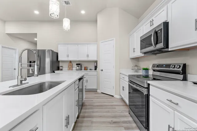 a kitchen with stainless steel appliances a stove top oven a sink a refrigerator and cabinets