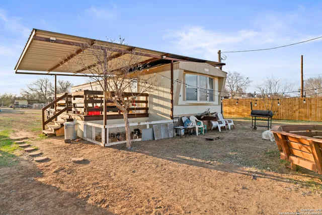 a backyard of a house with a large tree and wooden fence