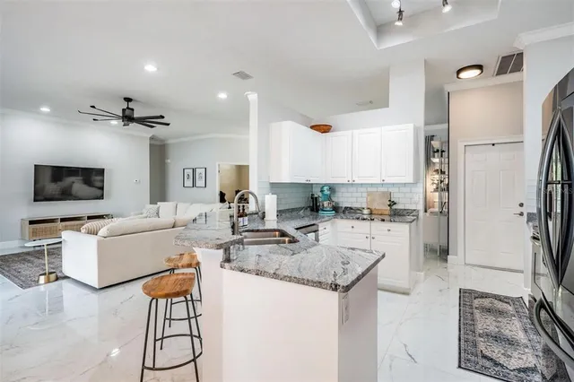 a view of a kitchen with kitchen island stainless steel appliances refrigerator stove dining table and chairs