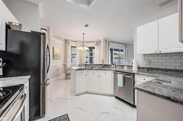 a kitchen with granite countertop a refrigerator stove and sink
