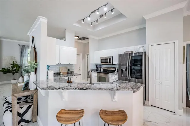 a kitchen with stainless steel appliances kitchen island granite countertop a refrigerator and a sink