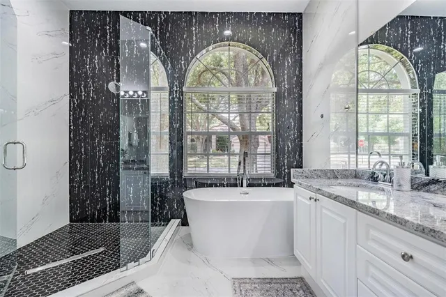 a bathroom with a granite countertop sink a large mirror and a bathtub