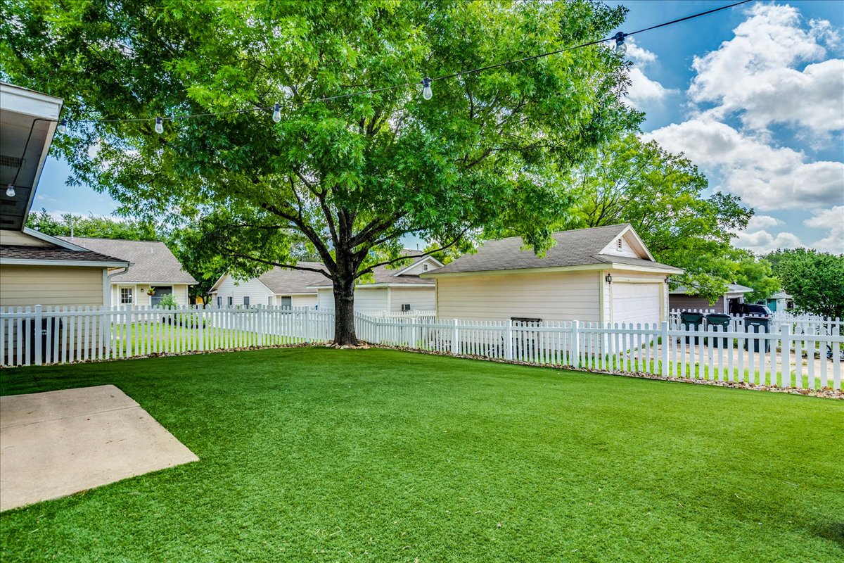 175 Wetzel Kyle, TX 78640 - Photo 26 of 27 A charming picket fence encloses a vibrant green yard, shaded by a mature tree.