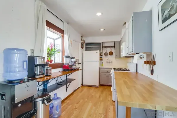 a kitchen with refrigerator a stove a sink dishwasher and wooden cabinets with wooden floor