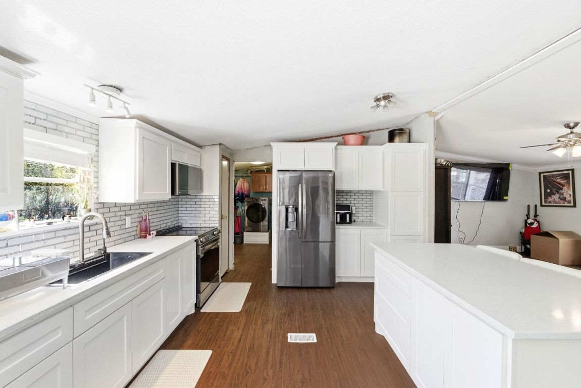 1485 Pettytown Road Dale, TX 78616 - Photo 10 of 36 a large white kitchen with a refrigerator a sink dishwasher a stove and a dining table with wooden floor