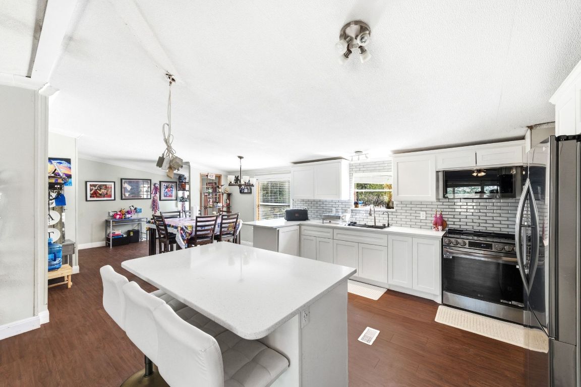 1485 Pettytown Road Dale, TX 78616 - Photo 7 of 36 a kitchen with stainless steel appliances kitchen island granite countertop a stove a refrigerator a oven a sink with island chairs and wooden floor