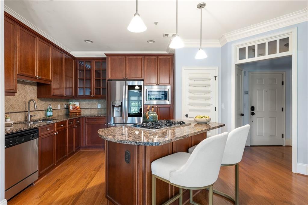 825 Highland Lane Northeast, Unit 1112 Atlanta, GA 30306 - Photo 12 of 39 a kitchen with stainless steel appliances granite countertop a kitchen island hardwood floor sink stove dining table and chairs