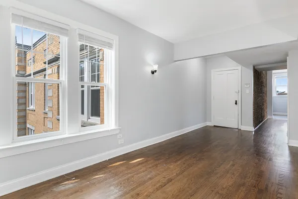 a view of an empty room with wooden floor and windows