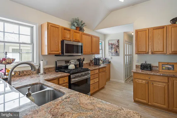 a kitchen with granite countertop a sink stove top oven and cabinets