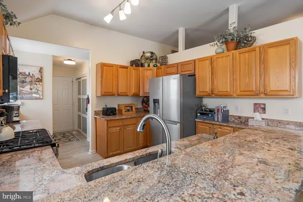 a kitchen with stainless steel appliances granite countertop a refrigerator a stove and a sink